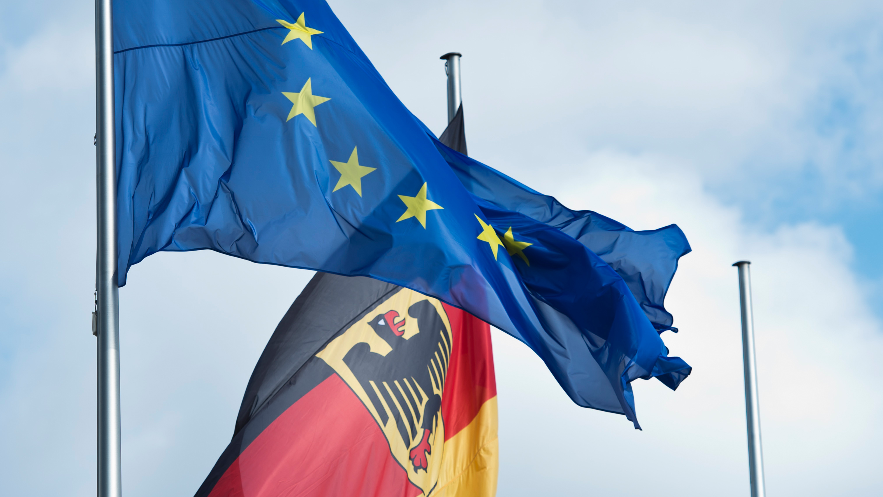 The flag of the European Union ( EU ) next to the flag of the Federal Republic of Germany 