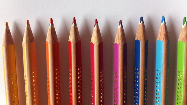 Generic image: Coloured crayons arranged in a straight row on a white background.