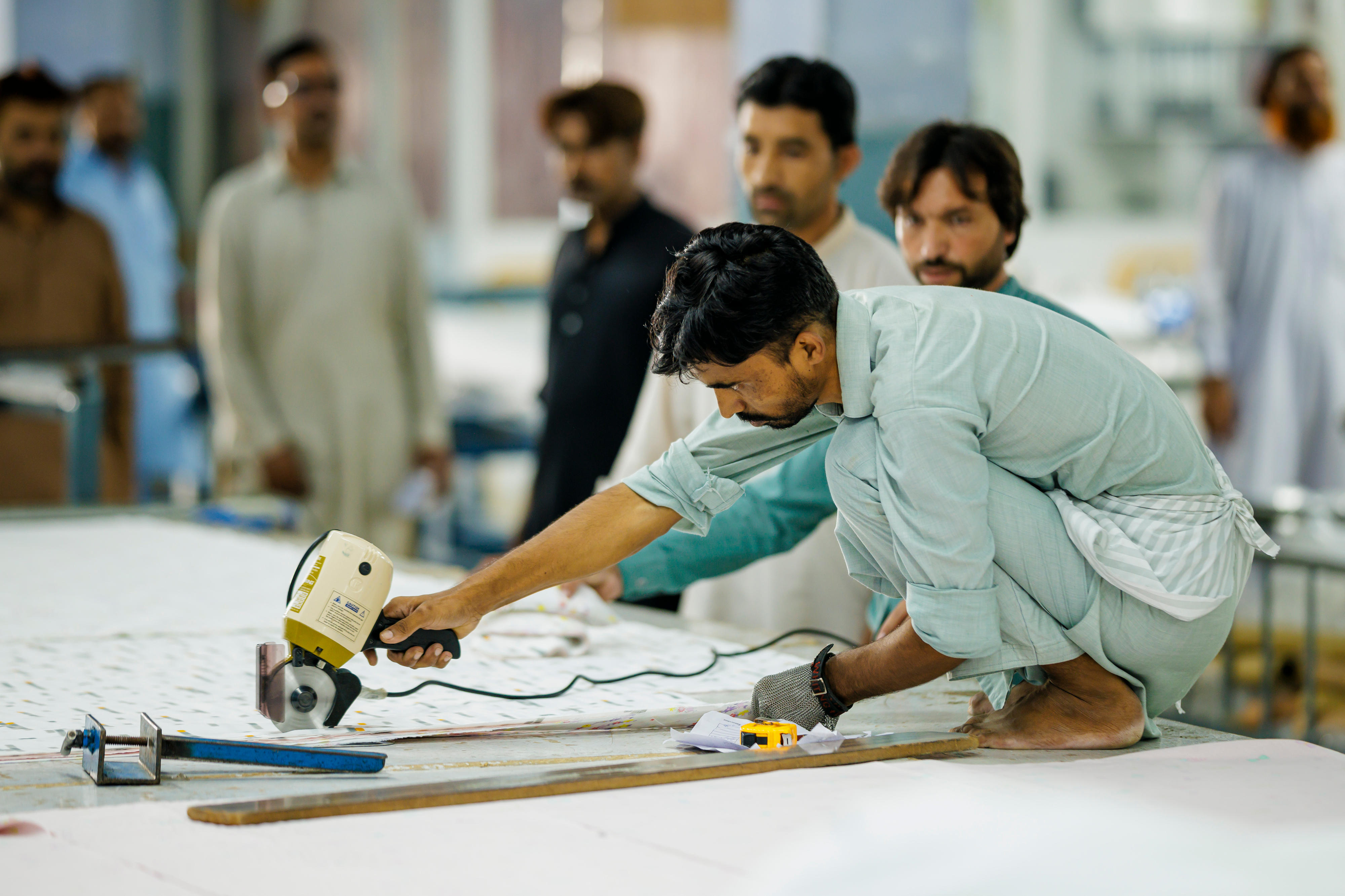 Ein Mitarbeiter der Textilfabrik Kohinoor Textile Mills Limited in Rawalpindi, Pakistan, schneidet Stoff zu.