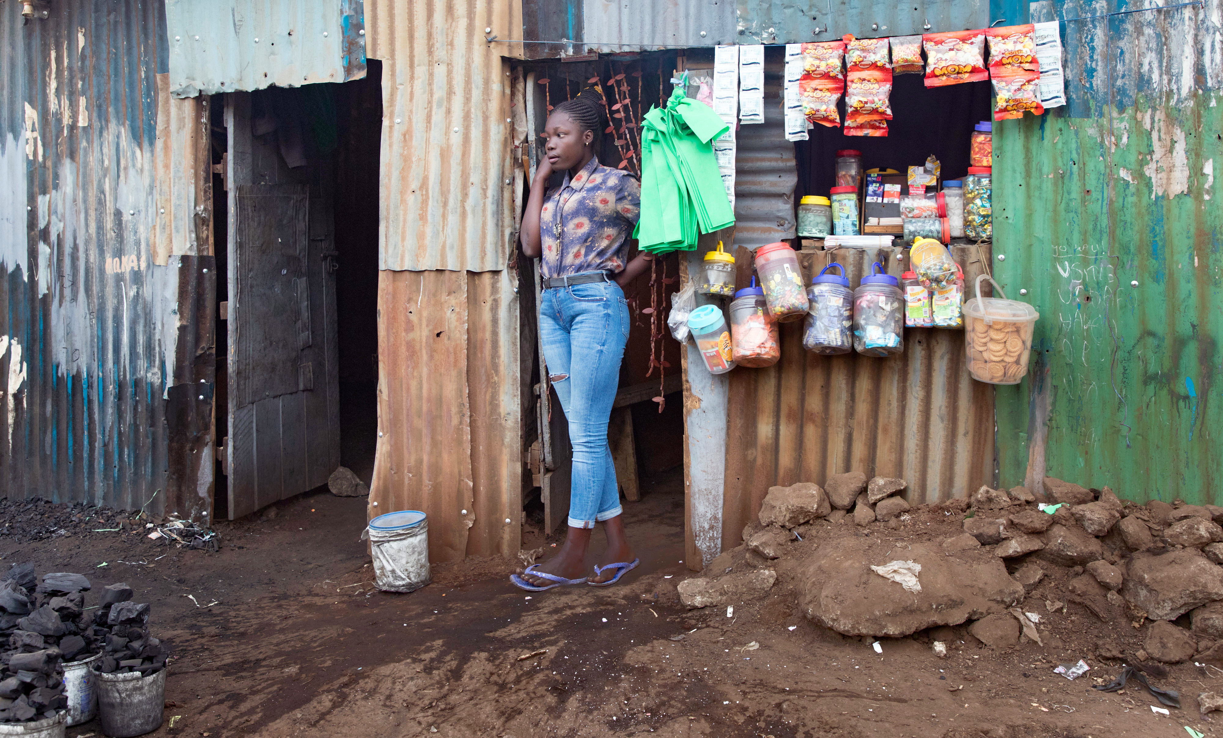 Young woman standing in front of her shop in Kibera, an informal settlement in Nairobi, Kenya